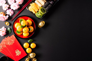 Chinese new year festival decorations pow or red packet, orange and gold ingots or golden lump on a black background. Chinese characters FU means fortune good luck, wealth, money flow.