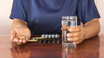 The hand of the patient taking the drug with a glass of water.