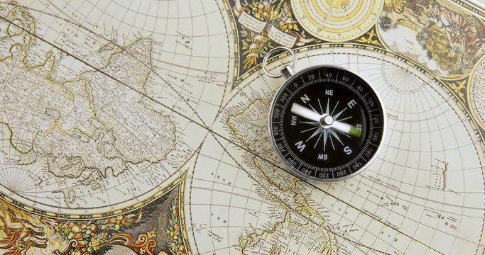 Disorientated spinning compass against map background closeup footage