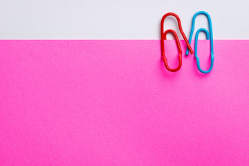 Lovely couple of paper clips hand in hand on pink paper for valentines day theme