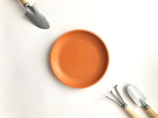 Gardening tools with saucer arranged on white background.