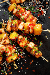 Grilled skewers with pineapple fruit and chicken meat  sprinkled with sesame seeds, herbs and...