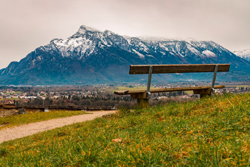 Alps mountains scenery landscape snowy range peak background with lonely wooden bench foreground...