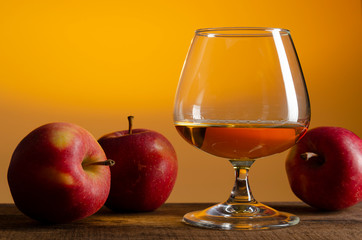 glass of Calvados Brandy and red apples on wooden