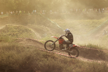 Fototapeta premium Motorcyclist in a motocross competition climbing up a dusty summer road