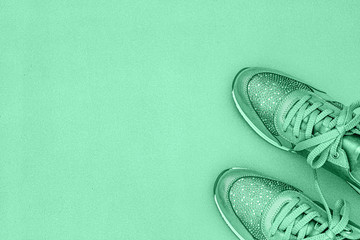Women's shoes with sequins, laces. Fashion frame glitter Women Sneakers, copy space, text place. Trendy fashionable Footwear in mint green color background, flat lay. Color trend 2020 Neo mint.