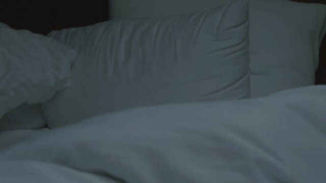 Messy white bedding after sleep in morning time. Comfort soft bed with sheet, pillows and duvet in home or hotel. Bedroom for background in b-roll.