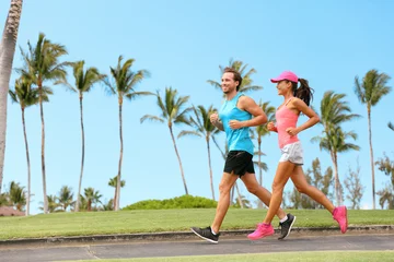 Outdoor-Kissen Healthy couple running together happy partner workout training outdoors in tropical city background. Woman and man jogging outside. © Maridav