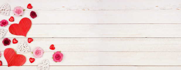 Valentines Day banner with corner border of hearts, flowers and decor against a rustic white wood background. Copy space.