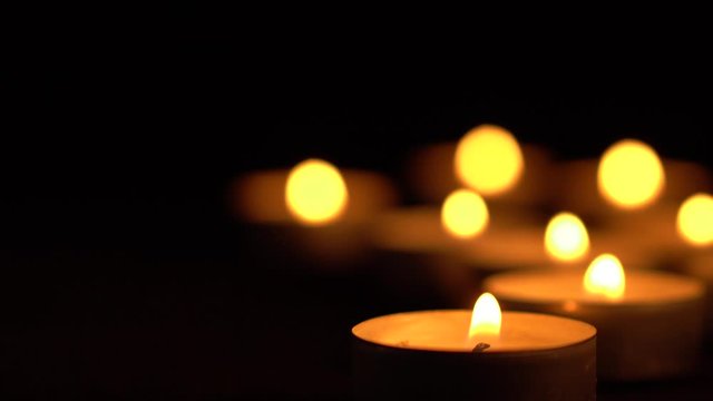 Slow motion white candles light up flames fire on isolated black background. Use in romantic dinner, warm and relax peace maditaion, use for spiritual religion church decotion and Halloween graveyard