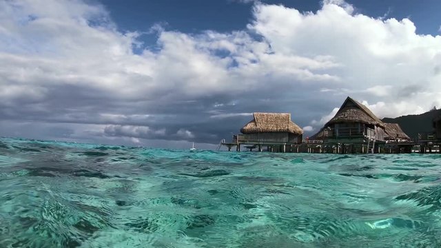 Overwater bungalow villas, turquoise lagoon. Underwater shot. Moorea, Tahiti French Polynesia. Luxury honeymoon vacation, romantic getaway, exotic resort destination.  