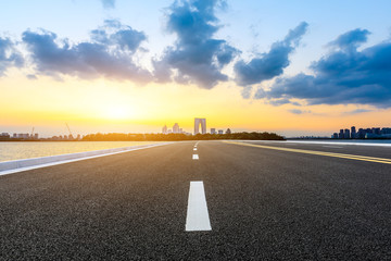 Empty asphalt highway and Suzhou city skyline with colorful sky at sunset.
