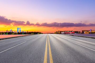 Empty asphalt highway and Suzhou city skyline with colorful sky at sunset.