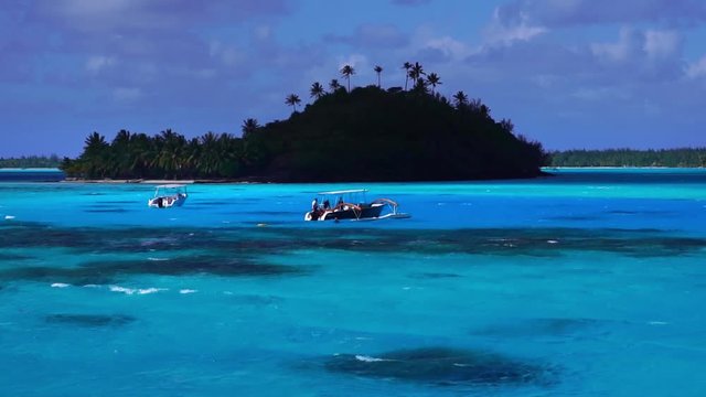 Low angle drone glide shot. Tourist boats in turquoise lagoon with coral reef. Bora Bora, Tahiti French Polynesia. Luxury honeymoon vacation, tropical romantic getaway, exotic resort destination.
