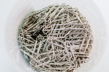 A lot of silver paper clip to white background.Magnetic box for put paper clips office supplies , business accessories.