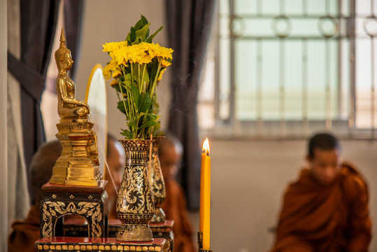 Buddha images and flower vases on the altar table in the Buddhist ceremony in Thailand