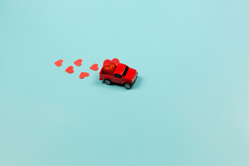 Valentines Day Theme Retro red toy car with red hearts on mint background. Copy Space for text. Minimalism Concept.