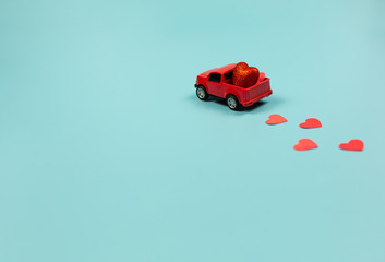 Valentines Day Theme Retro red toy car with red hearts on mint background. Copy Space for text. Minimalism Concept.