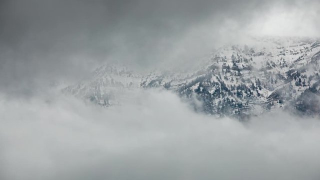 Mountains peaking out through clouds rolling in timelapse through the sky after a storm.