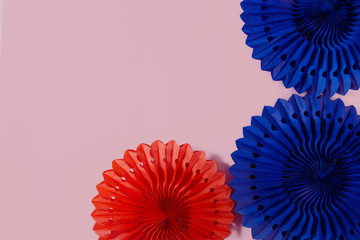 Bright blue and orange trendy colors of blue and orange paper fans and honeycombs party decor on rose color background. 