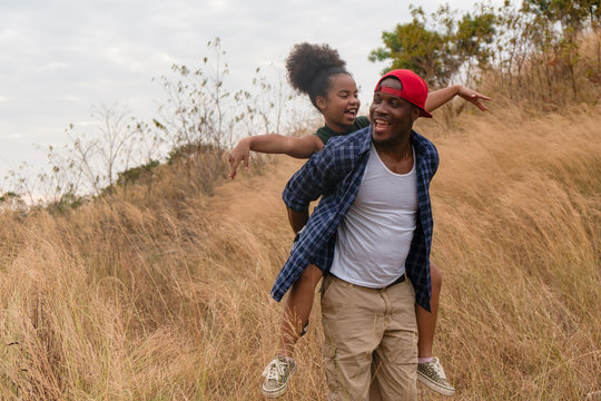 african american father and daughter having fun playing piggyback together during traveling countryside