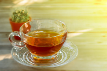 amber tea in a clear-colored teacup is placed on a vintage wooden table background