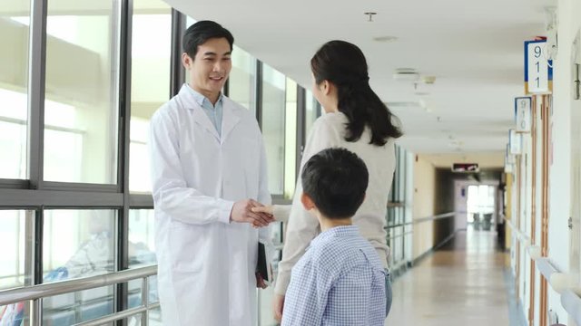 young asian doctor talking to mother and child in hospital hallway