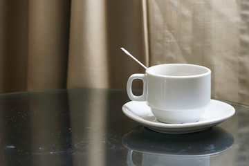 A white coffee cup with  plastic spoon inside over wooden background