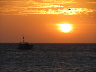Naklejka na ściany i meble Fishing boat starting work at sunset.
