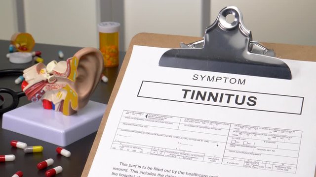 Tinnitus patient diagnosis on a medic office with pills, stethoscope and anatomy models. Camera panning reveling the notebook with the medical record copy.