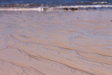 Beach sand. Waves and the sea in the background out of focus.