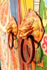 Brass door knobs are on bright colorful door and shape tiger head, the door knobs are design chinese style in shrine, Thailand.