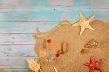 Papyrus from the glass bottle with cork. Starfish with seashells on sand and blue wooden background.
