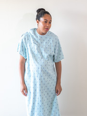 A young postpartum mixed race African American woman wearing a hospital gown or robe hunches over...