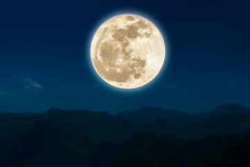 Full moon over silhouette mountain at night.