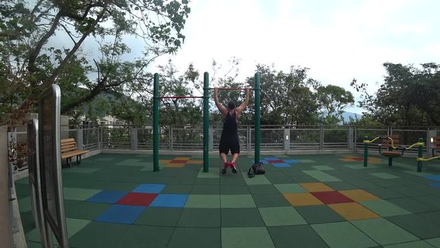 Junger Mann macht Klimmz&uuml;ge im Park an einem calisthenics  Platz