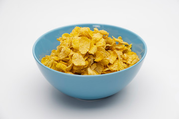 Golden cornflakes in the blue bowl isolated on white background