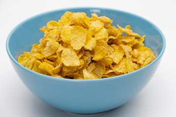 Golden cornflakes in the blue bowl isolated on white background