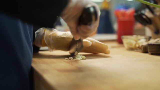 Roughly chopping garlic for a sauce that is being made.