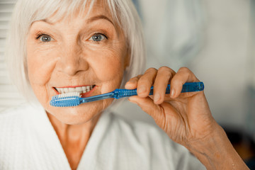 Lovely old lady brushing teeth in the morning