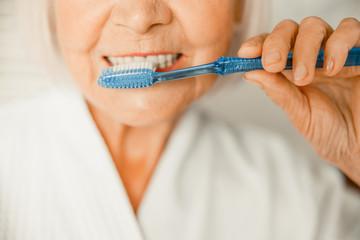 Old woman brushing teeth in the morning