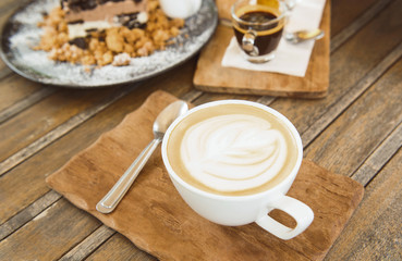 Picture of coffee cup And pastries placed on a vintage style wooden table.