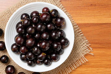 Jabuticaba in the bowl on jute - top view. Jaboticaba or Jabuticaba is the native Brazilian grape tree. Species Plinia Cauliflora. Brazilian Berry.