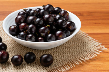 Jabuticaba in the bowl on jute. Jaboticaba or Jabuticaba is the native Brazilian grape tree. Species Plinia Cauliflora. Brazilian Berry.