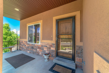 Home exterior view with porch and glass door in front of the brown front door