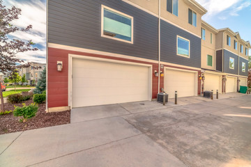 Exterior of three storey townhomes with garages and red gray and beige walls