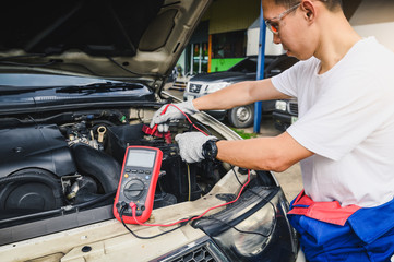 The abstract image of the technician using voltage meter for voltage measurement a car's battery. the concept of automotive, repairing, mechanical, vehicle and technology.