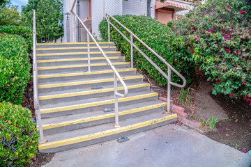 Cement entrance steps with yellow warning on a sunny day