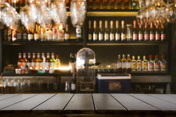 Empty wooden bar counter with defocused background and bottles of restaurant, bar or cafeteria background. - obrazy, fototapety, plakaty