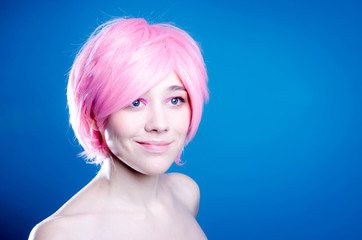 Beautiful cheerful girl with pink hair on blue background